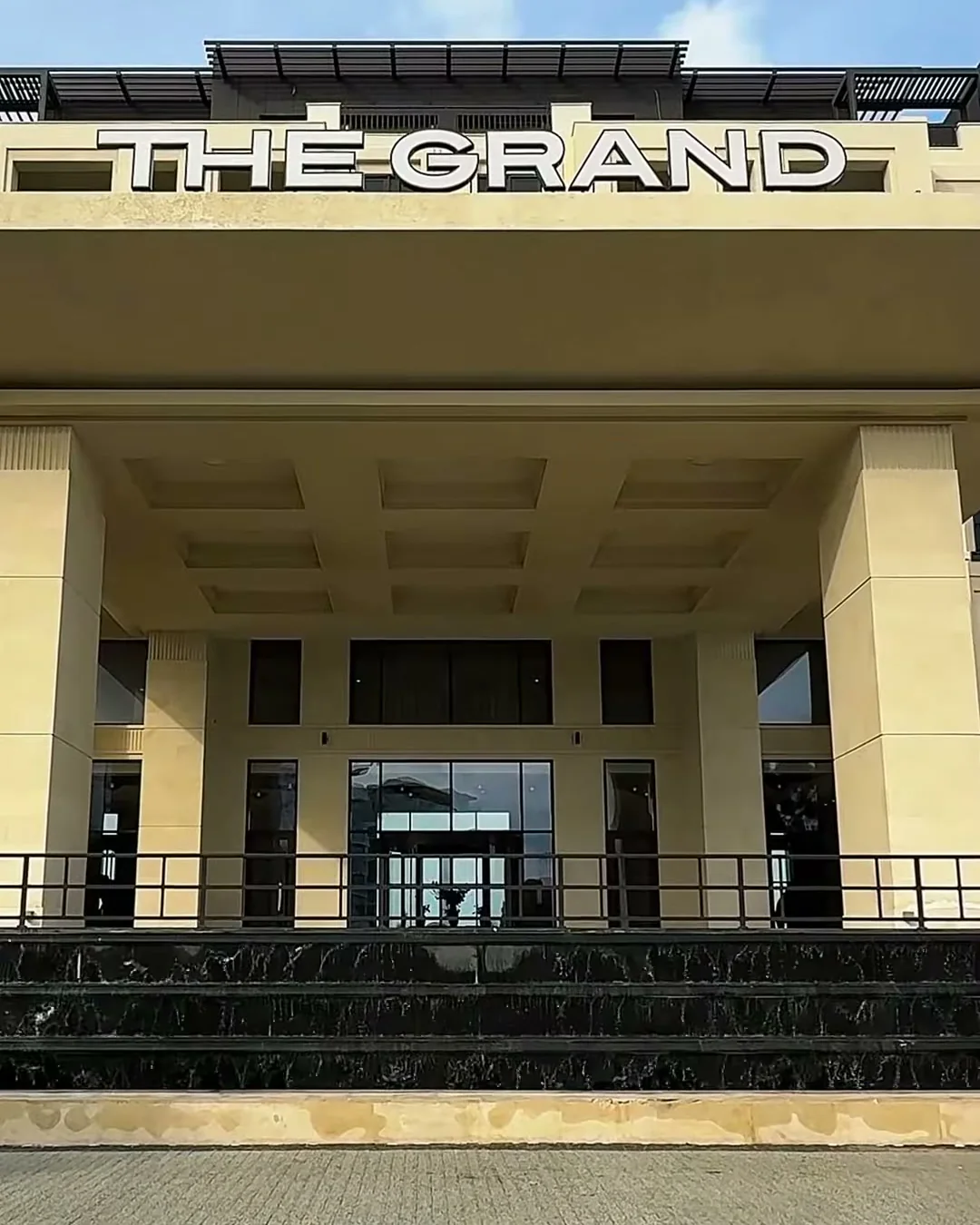 Главный вход The Grand с южной стороны — ориентир: аптека от него восточнее, по той же линии фасада